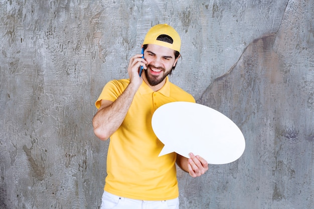 Free Photo service agent in yellow uniform holding ovale info board and talking to the phone