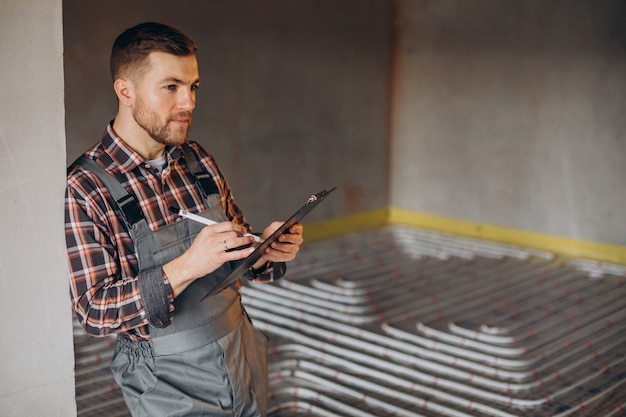 Free Photo service man instelling house heating system under the floor