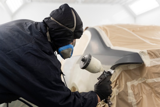 Service worker painting car in auto service