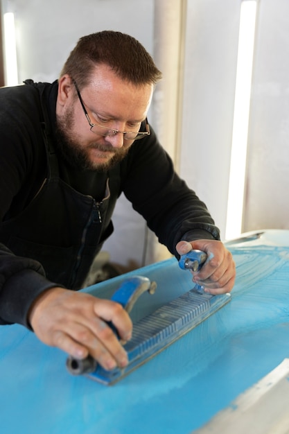 Service worker painting car in auto service