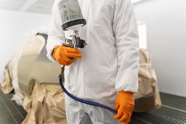 Service worker painting car in auto service