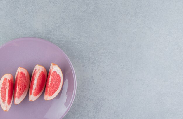 A serving of grapefruit slices on a platter on marble 