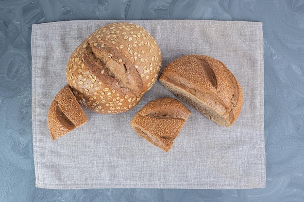 Sesame covered sliced lumps of bread on a towel on marble surface.