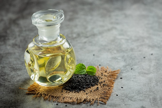 Sesame oil and raw black sesame seeds on dark background