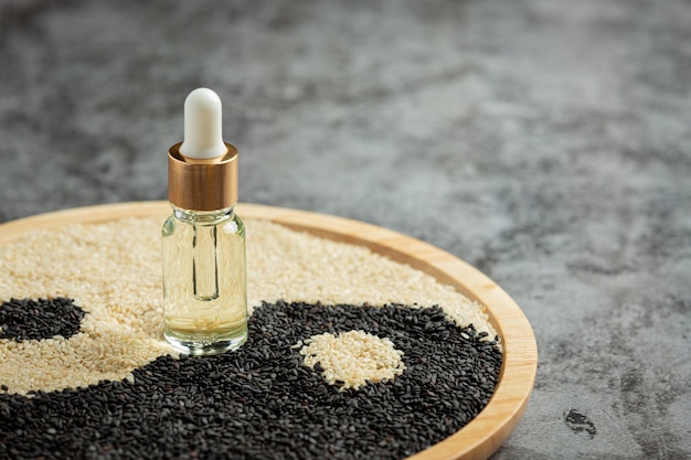 Free Photo sesame oil and sesame seeds on dark background