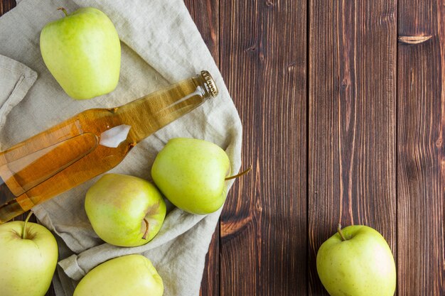 Set of apple juice and green apples on a cloth and wooden background. flat lay. space for text