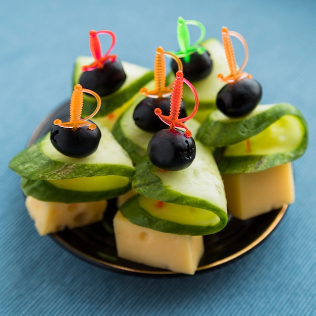 Free Photo set of cheese, olive and cucumber on plastic skewer on plate