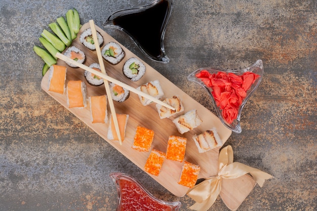 Set of delicious sushi with chopsticks and ginger on marble surface