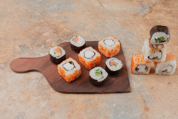 Set of delicious sushi on wooden plate