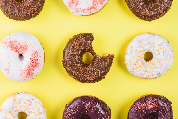 Free photo set of different colored round frosting donuts with bite mark