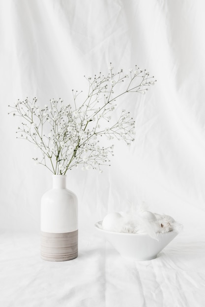 Free photo set of easter eggs and quills in bowl near plant twigs in vase