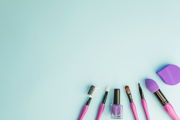 Set of essential professional make-up brushes; nail varnish and sponge over colored background