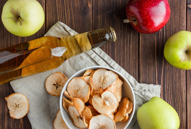 Set of fresh apple and juice and dried apples in a bowl on a cloth and wooden background. top view.