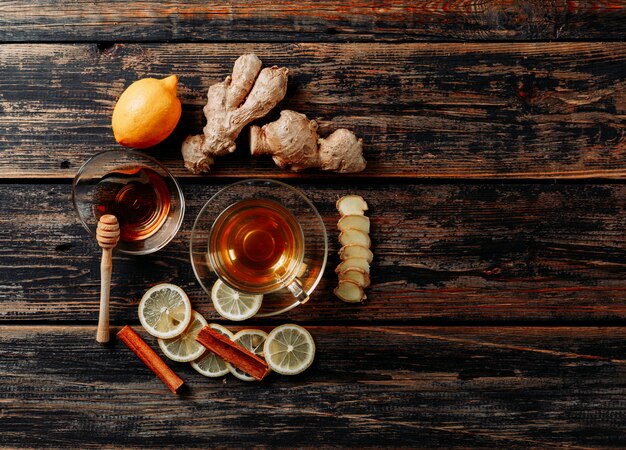 Set of ginger, honey, dry cinnamon, tea and green and lemon on dark wooden background. top view. space for text