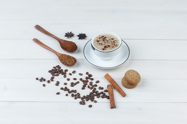 Free photo set of grinded coffee, spices, coffee beans, cookies and coffee in a cup on a wooden background. high angle view.