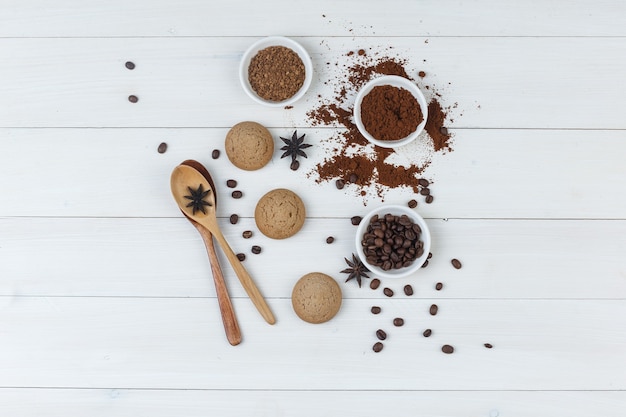 Free Photo set of grinded coffee, spices, cookies, wooden spoons and coffee beans in a bowl on a wooden background. top view.