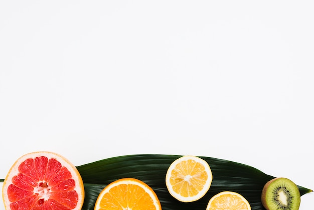 Free Photo set of half of tropical fruits on banana leaf on white background