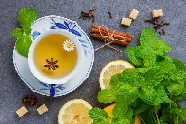 Set of mint leaves, lemon, sugar, dry cinnamon and a cup of chamomile tea