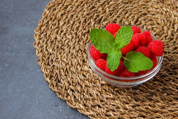 Set of mint leaves and raspberries in a saucers on a trivet