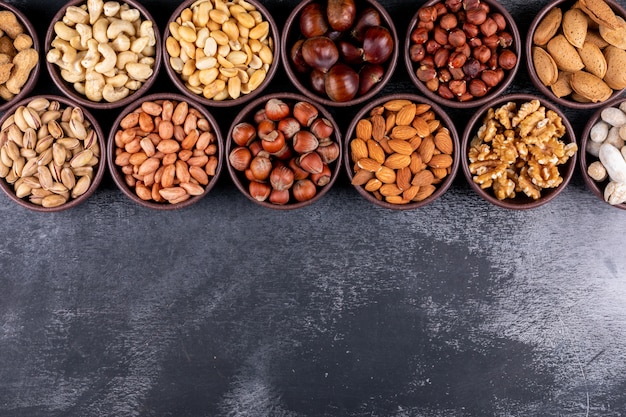 Set of pecan, pistachios, almond, peanut, and lined up assorted nuts and dried fruits in a mini different bowls