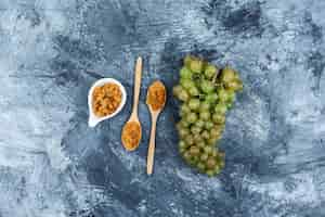 Free photo set of raisins and green grapes on a grungy plaster background. top view.