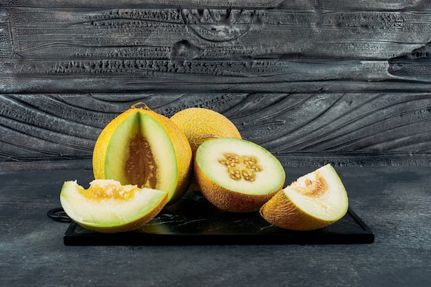 Free Photo set of split in half melon and sliced melons on a dark wooden background. side view.