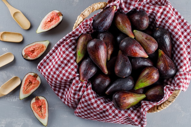 Free photo set of spoons and mission figs and halves in a picnic basket on a gray background. top view.