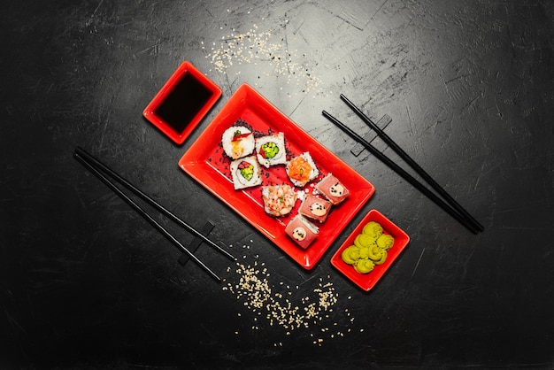 Set of sushi, Japanese knife, chopsticks and on dark stone table. 