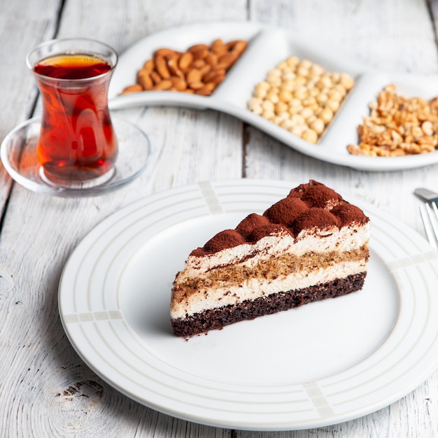 Set of tea, nuts and delicious dessert in a plate on a white wooden background. high angle view.