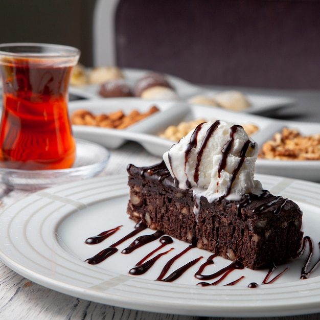 Set of tea, nuts and dessert in a plate on a white wooden background. side view.