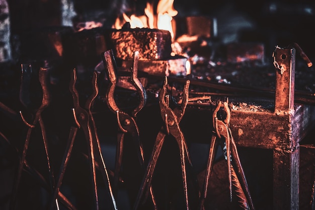 Free photo set of tools with gleam of fire at dark blacksmith workshop.