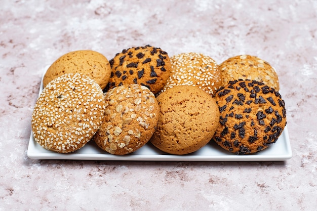 Set of various american style cookies on a light concrete background. Shortbread with confetti, sesame seed, peanut butter, oatmeal and chocolate chip cookies.