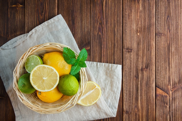 Set of white cloth and lemons in a basket on a wooden background. top view.