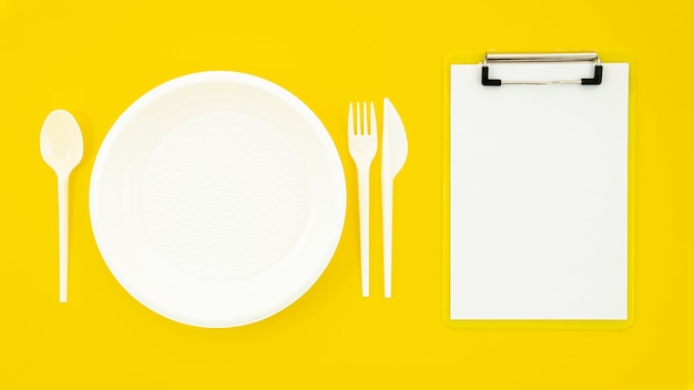 Free Photo set of white dish and clipboard on yellow background