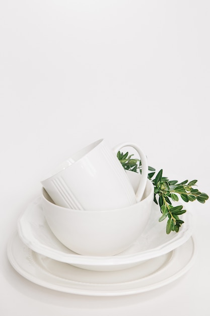 Free Photo set of white dishes of three plates and a cup decorated with a branch of eucalyptus