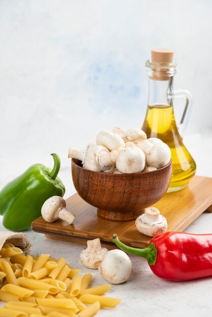 Set of white mushrooms, pastas, chili peppers and extra virgin olive oil on the marble.