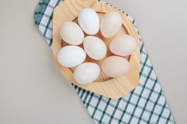 Several fresh chicken white eggs on wooden plate .