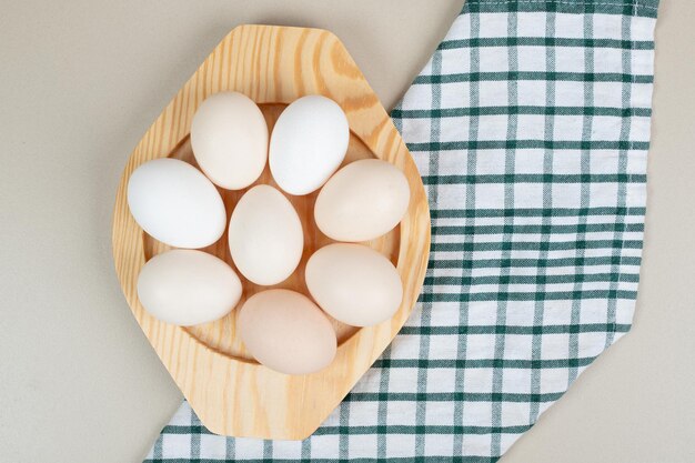 Several fresh chicken white eggs on wooden plate .