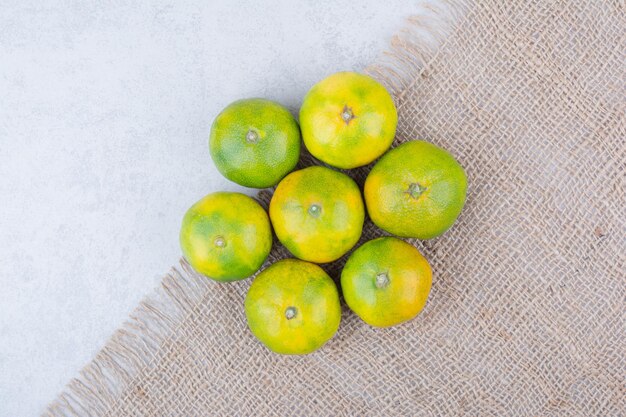 Several fresh sour whole tangerines on sackcloth . High quality photo