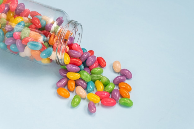 Several Jelly Beans on the blue surface inside the glass pot