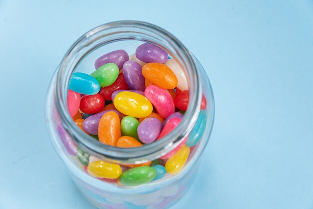 Several Jelly Beans on the blue surface inside the glass pot