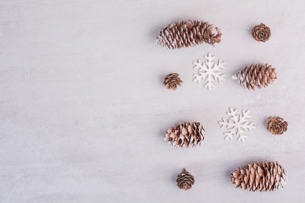 Free photo several pine cones and snowflakes on white surface