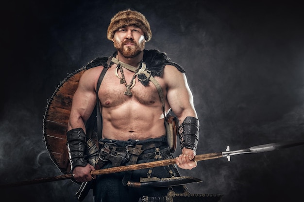 Free Photo severe barbarian in warrior clothes, posing on a dark background.