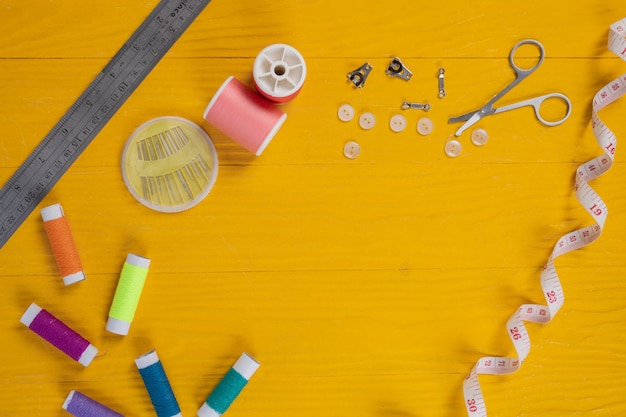 A sewing kit, needle, thread, a needle, placed on a yellow wooden floor.