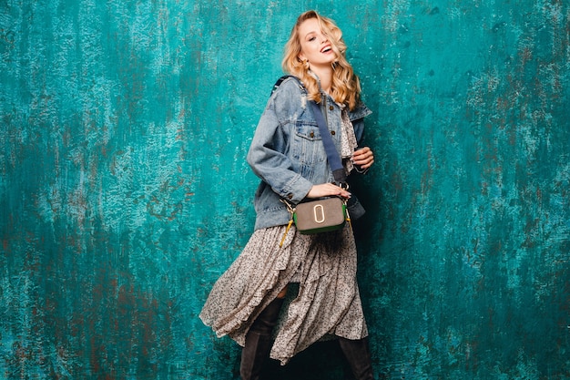 Free photo sexy attractive stylish blonde woman in jeans and oversize jacket walking against vintage green wall in street