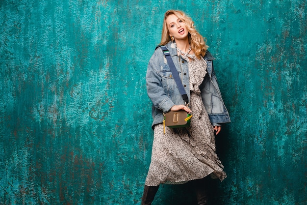 Free photo sexy attractive stylish blonde woman in jeans and oversize jacket walking against vintage green wall in street