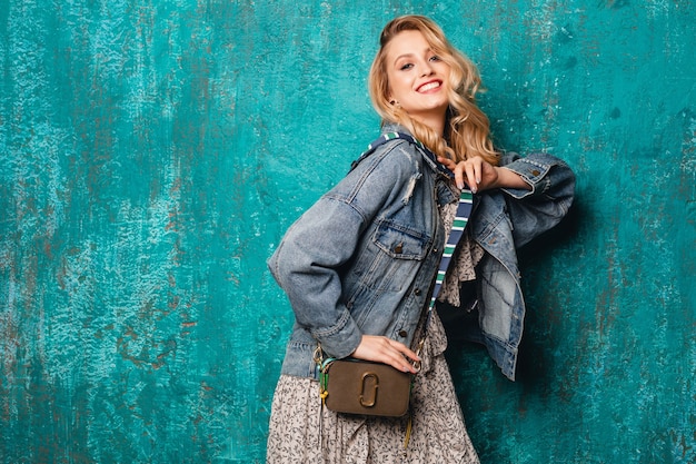 Free photo sexy attractive stylish blonde woman in jeans and oversize jacket walking against vintage green wall in street