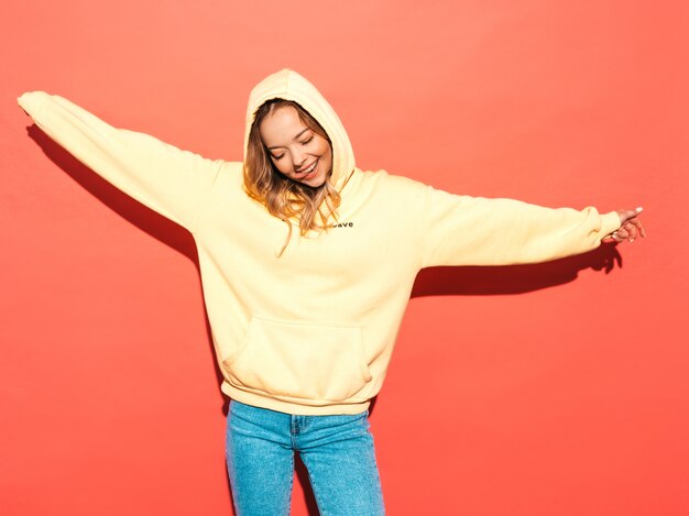 Sexy carefree woman posing near pink wall. Positive model having fun.Raising her hands