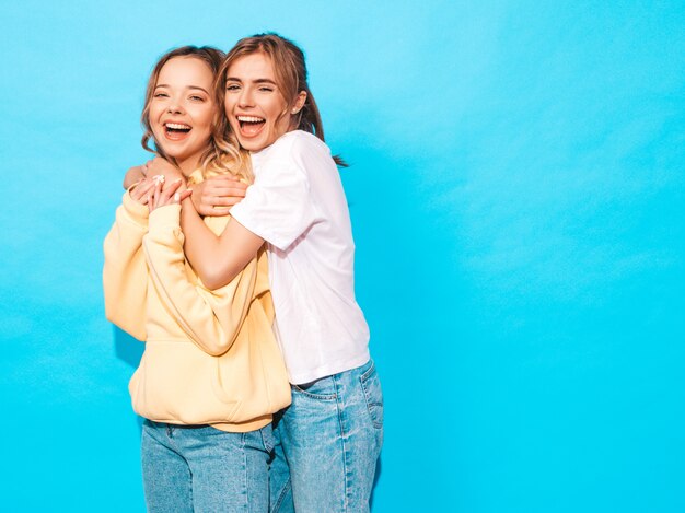 Sexy carefree women posing near blue wall. Positive models having fun