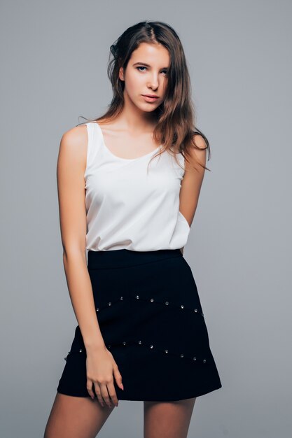 Sexy girl in fashion modern dress is posing in studio holds her arms on hair isolated on white background